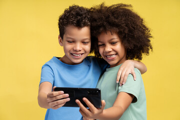 Happy African American friends holding mobile phone, using mobile app, watching video