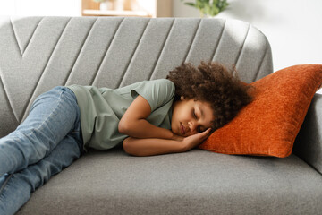 Cute little girl child sleeping on couch sofa with soft pillows at living room at home