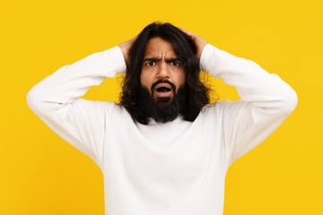 Frustrated Man Grasping His Head in Disbelief Against Yellow