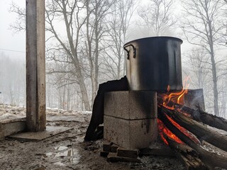 Maple sap boiling in a large pot over a fire to evaporate down into maple syrup