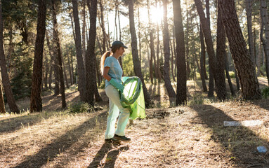 Responsible Hiker Picking Up Trash in the Forest at Sunset
