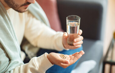 Man Holding Pills and Glass of Water at Home