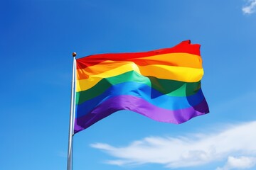 Rainbow flag waving against a clear blue sky