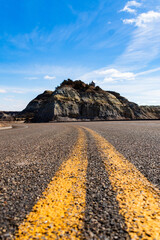 Low angle photo of highway in foreground and Theodore Roosevelt National Park in the Background