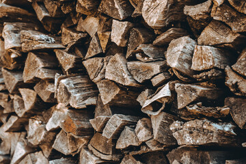 Chopped firewood pile. Woodpile wall. Heap of old dry pine woods. Brown textured background. Natural solid fuel resources. Winter preparation. Countryside pattern. Rustic style details. Woodworking