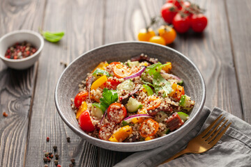 Easy vegetarian salad of fresh cucumber, quinoa cereal, tomato, sweet pepper and onion in bowl ....
