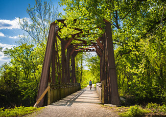 View of railroad bridge  converted into recreational trail in summer; male bicyclist riding  in...
