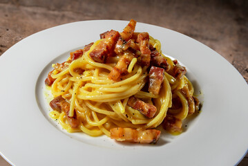 Spaghetti carbonara in white plate on wooden table