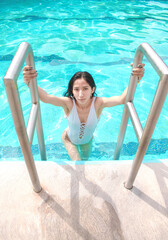 Joven mujer delgada saliendo de la piscina en sus vacaciones 
