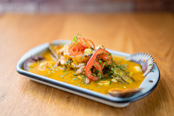 Parhuela or special seafood soup with crab, mussels and cassava, decorated with seaweed and served in a white bowl
