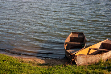 Two rowboats are moored to the shore. Metal boats are attached to the shore with steel chains....