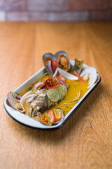 Parhuela or special seafood soup with crab, mussels and cassava, decorated with seaweed and served in a white bowl