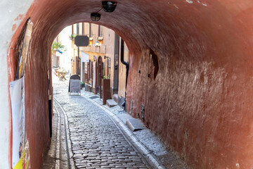 Stockholm destination Sweden. Arched stonewall covers narrow paved alleyway at Gamla Stan Old Town.