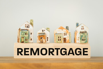 REMORTGAGE, a word written on a wooden block with miniature houses. Real estate business and financial concept, copy space