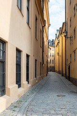 Narrow paved alleyway between building background at Gamla Stan Old Town, Stockholm Sweden. Vertical