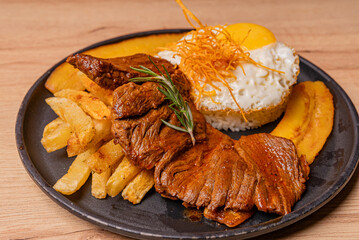 Poor style steak, potatoes and fried plantains, as well as white rice with its egg whipped with the yolk.