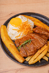 Poor style steak, potatoes and fried plantains, as well as white rice with its egg whipped with the yolk.
