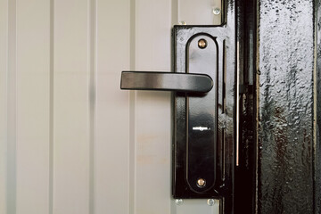 Street gate with corrugated sheet covering and black door knob and lock close-up - 799366079