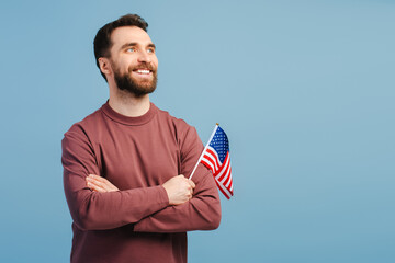 Confident smiling man holding American flag isolated on blue background