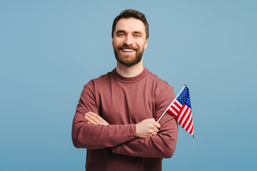 Portrait of handsome, attractive man wearing stylish casual clothes holding American flag