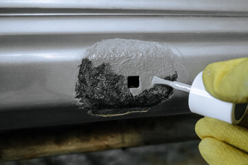 Applying epoxy primer with a brush to part being repaired of damaged galvanized car body. Car sill close-up. - 799367671