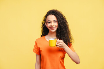 Photo of delightful smiling young girl, teenager in t-shirt, holding cup of coffee, isolated