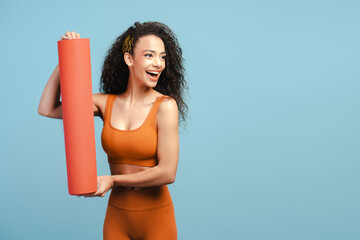 Happy smiling teenager, with muscular strong body looking away, holding fitness yoga mat