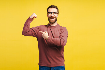 Excited fitness man wearing casual clothes showing arms pointing at muscles