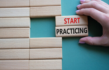 Start Practicing symbol. Concept word Start Practicing on wooden blocks. Beautiful grey green background. Businessman hand. Business and Start Practicing concept. Copy space