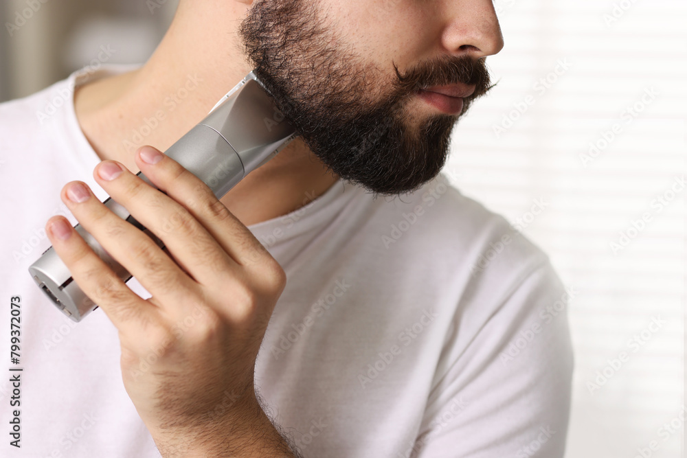 Poster Handsome young man trimming beard at home