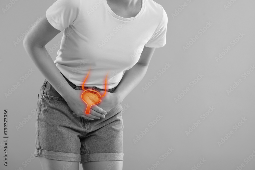 Wall mural Woman suffering from cystitis on light grey background, closeup. Illustration of urinary system