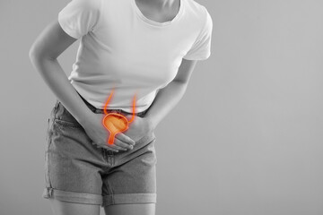 Woman suffering from cystitis on light grey background, closeup. Illustration of urinary system