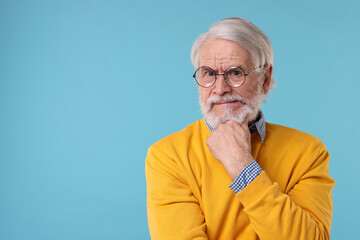 Portrait of stylish grandpa with glasses on light blue background, space for text