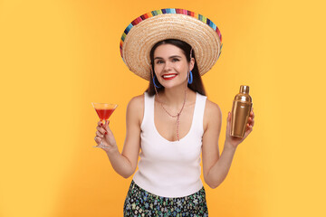 Young woman in Mexican sombrero hat with cocktail and shaker on yellow background