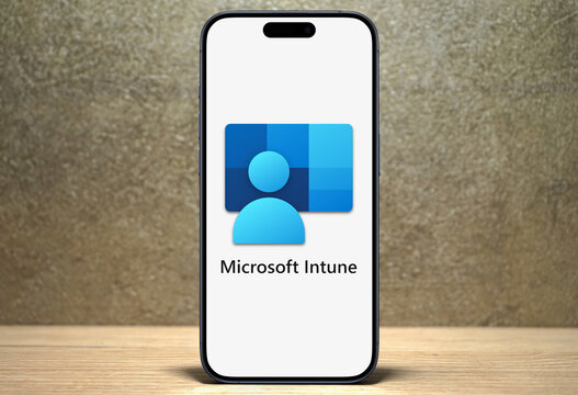 Microsoft Intune logo displayed on a modern smartphone standing on a wooden desk, cloud-based unified endpoint management service, Microsoft Azure