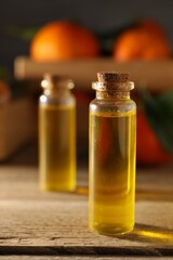 Bottles of tangerine essential oil on wooden table, closeup