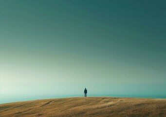 Man standing alone on a hilltop overlooking the ocean