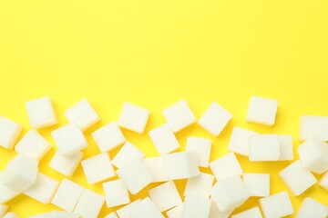 White sugar cubes on yellow background, top view. Space for text