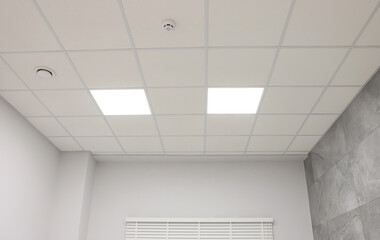 White ceiling with PVC tiles and lighting indoors, low angle view