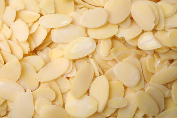 Fresh almond flakes as background, top view