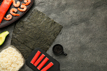 Flat lay composition with ingredients for sushi on dark textured table. Space for text