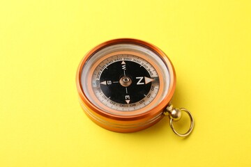 One compass on yellow background, closeup. Tourist equipment