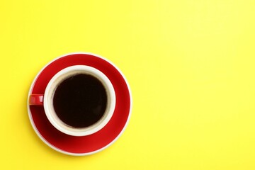 Aromatic coffee in cup on yellow background, top view. Space for text