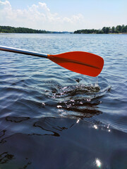 The oar of a red boat on the background of the water of a wide river