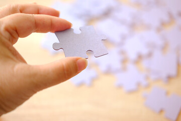 female hand holds cardboard puzzle piece, logical skills, puzzle solving and memory improvement,...