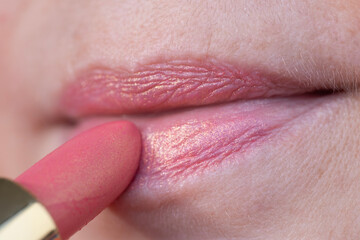Close-up of pink iridescent lipstick coloring female lips, enhancing beauty and style, showcasing...