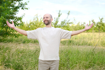 romantic young man stands in vibrant field, arms outstretched as embracing beauty and tranquility...
