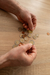 poor pensioner, Senior man lays out euro cent coins on wooden table, counts meager cash money on...