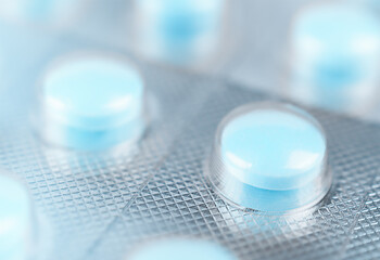 Blue tablets in blister. Macro shot. Stock photo.