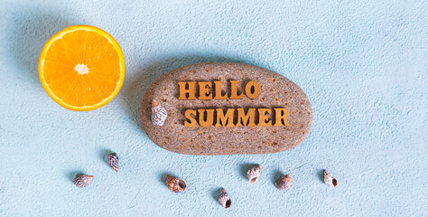 Concept hello summer text on stone, half orange and seashells on blue background top view web banner